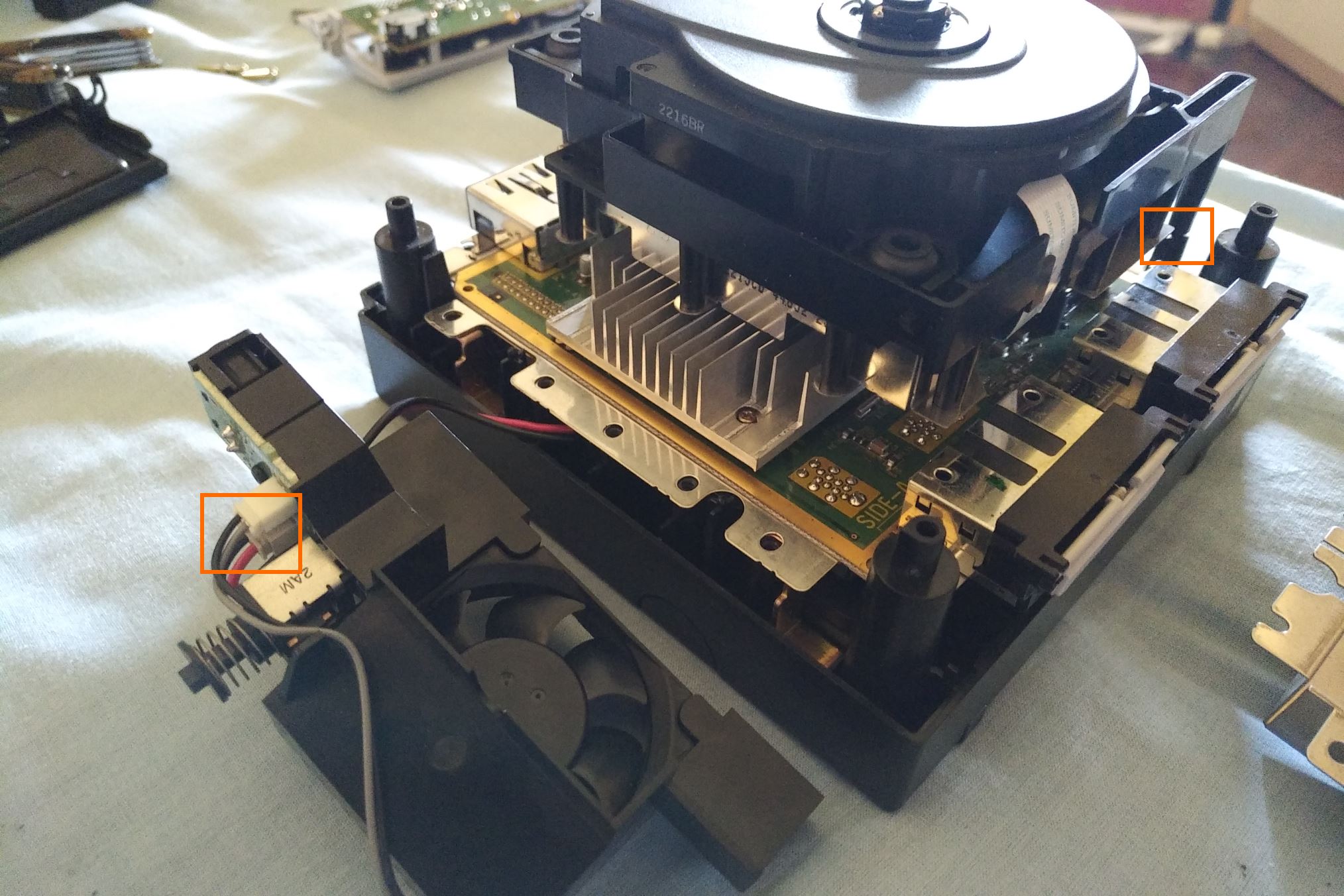 Console parzialmente riassemblata, con cavo di alimentazione (passaggio 5) ricollegato all'interruttore, e lettore rimontato senza la base metallica